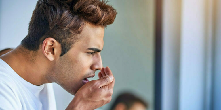 Shot of a handsome young man smelling his breath during his morning grooming routine.